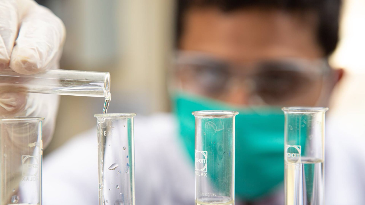 Laboratory technician at Usama Clinical Laboratory transferring a sample between test tubes